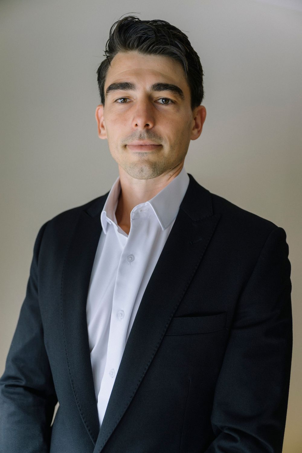 Professional headshots showing different expressions in formal attire against a neutral background.