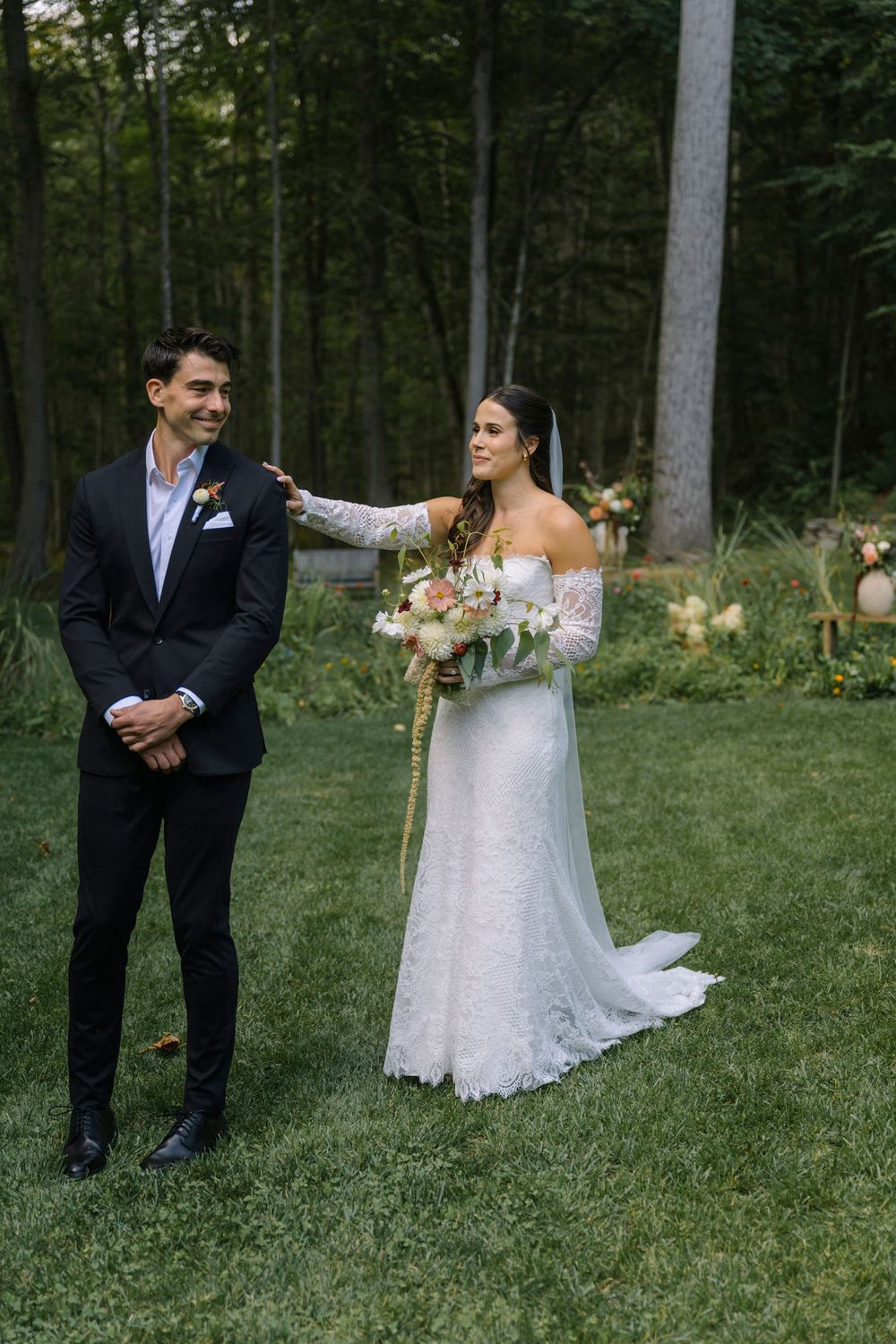 A romantic wedding photoshoot in a lush garden setting with a couple in formal attire among tall trees.