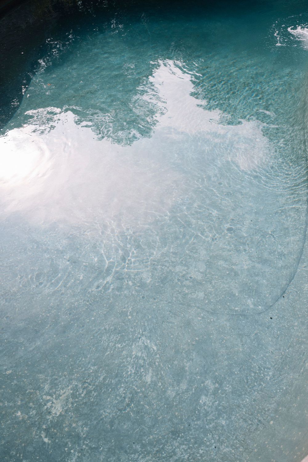 Turquoise blue water surface with white foam and ripples creating an abstract aquatic pattern.
