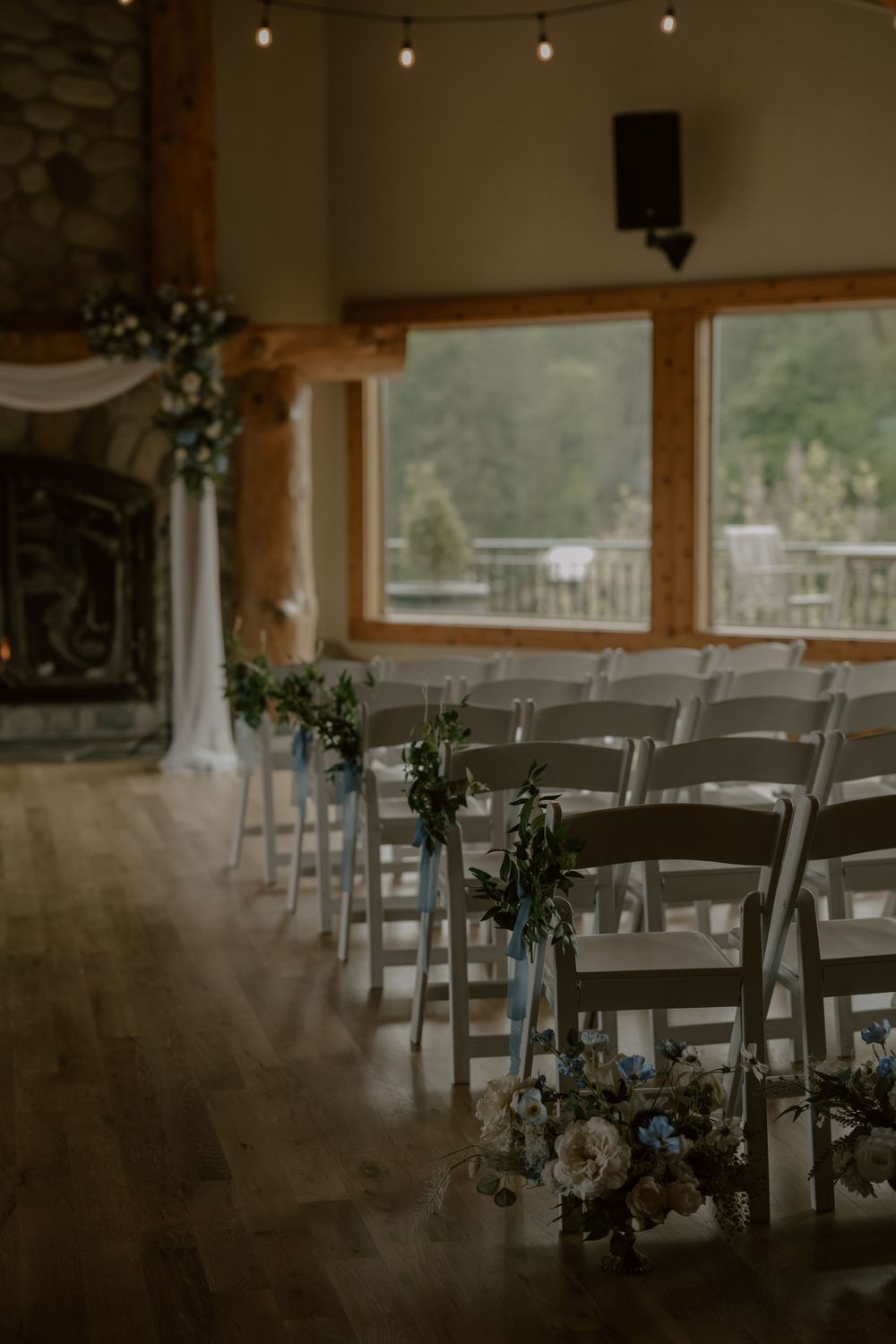Wedding ceremony space with rows of chairs decorated with floral arrangements and mountain views.