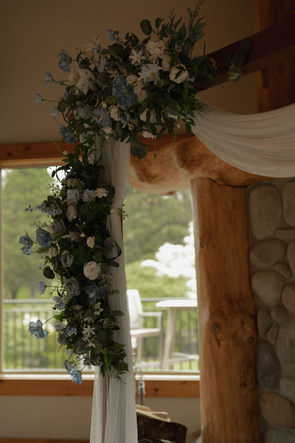 Elegant floral arch with blue and white flowers draped in white fabric for a wedding ceremony.