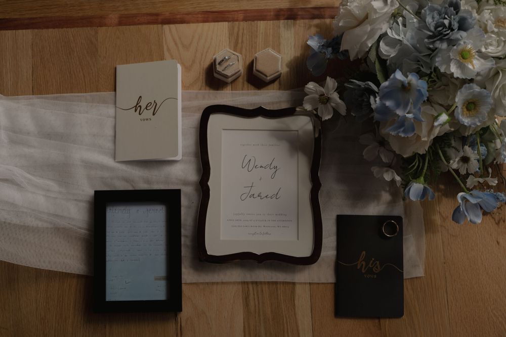 Wedding stationery and decorative items arranged with floral decor on white linen.