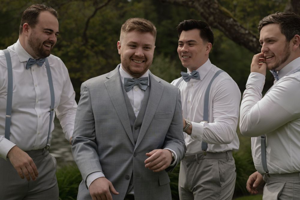 Candid moment of groomsmen laughing together in formal wear.