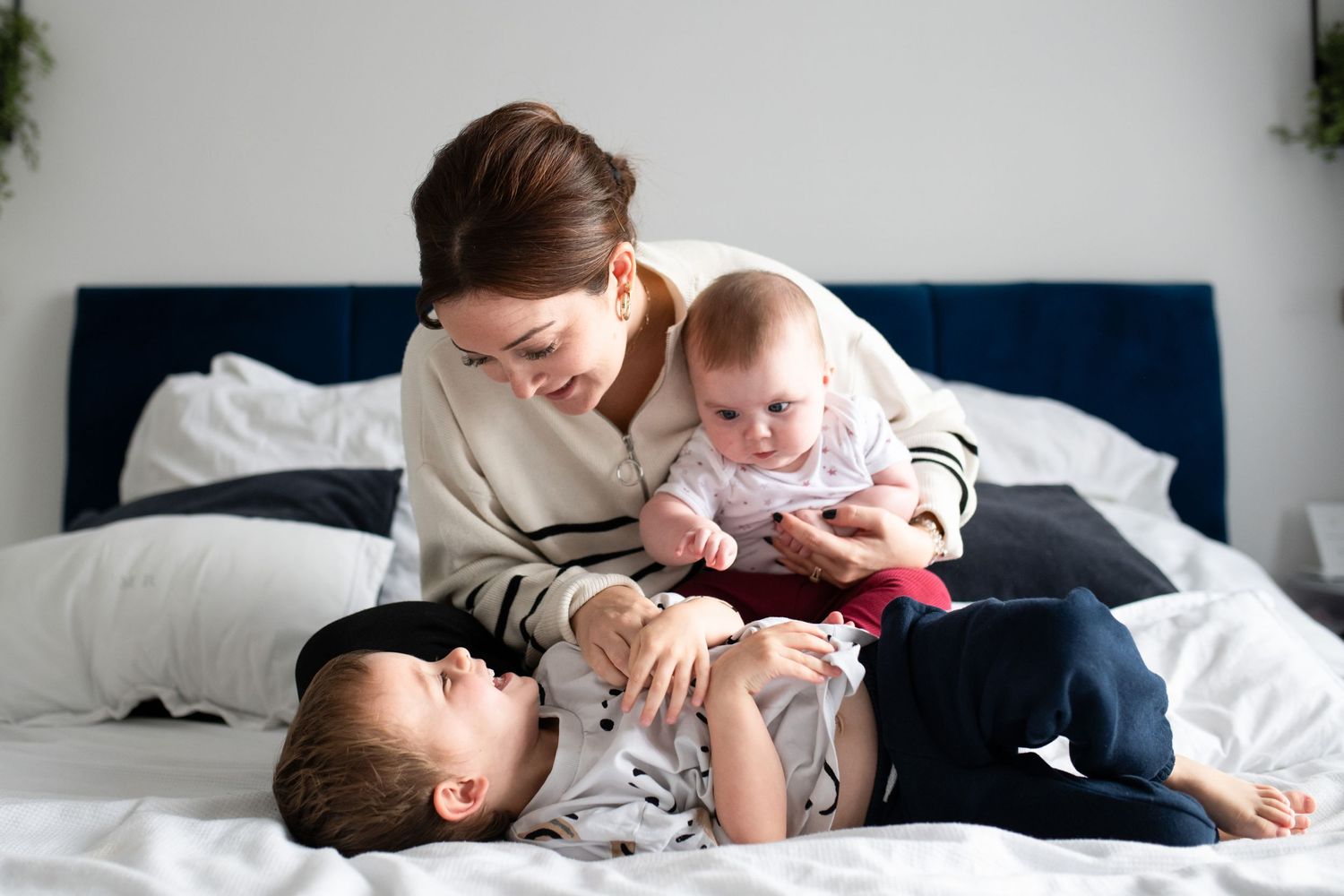 Mum and her two little ones on the bed having tickles, Sarah Frame Photography - Newborn - Surrey