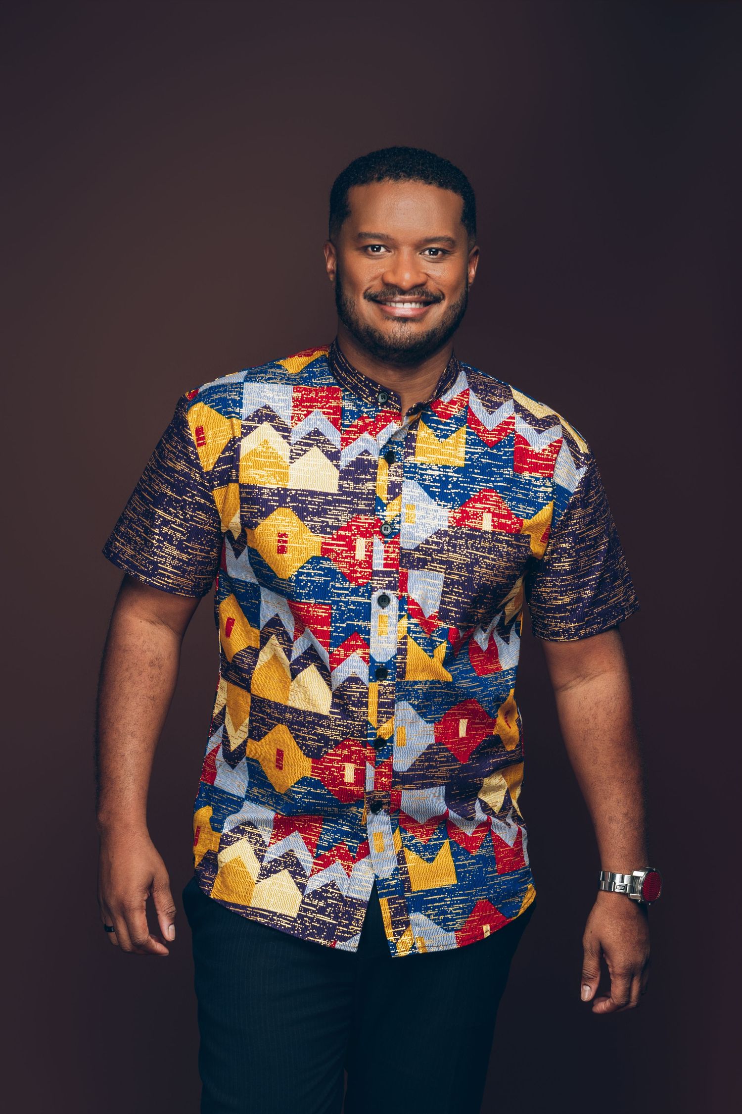 Portrait of a smiling person in a black shirt with hand touching their face.