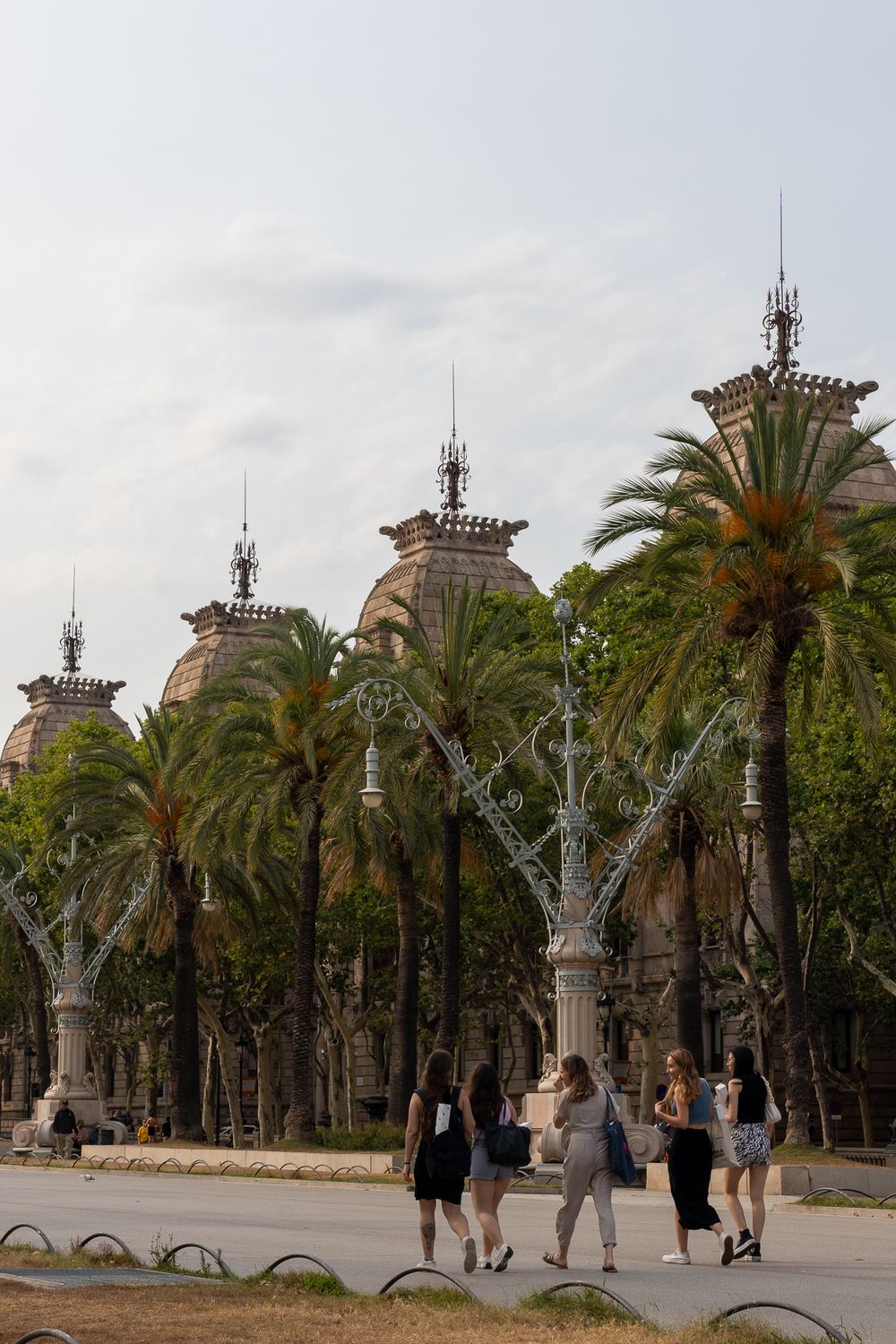 Palm tree-lined promenade with ornate architectural details in Barcelona's cityscape.