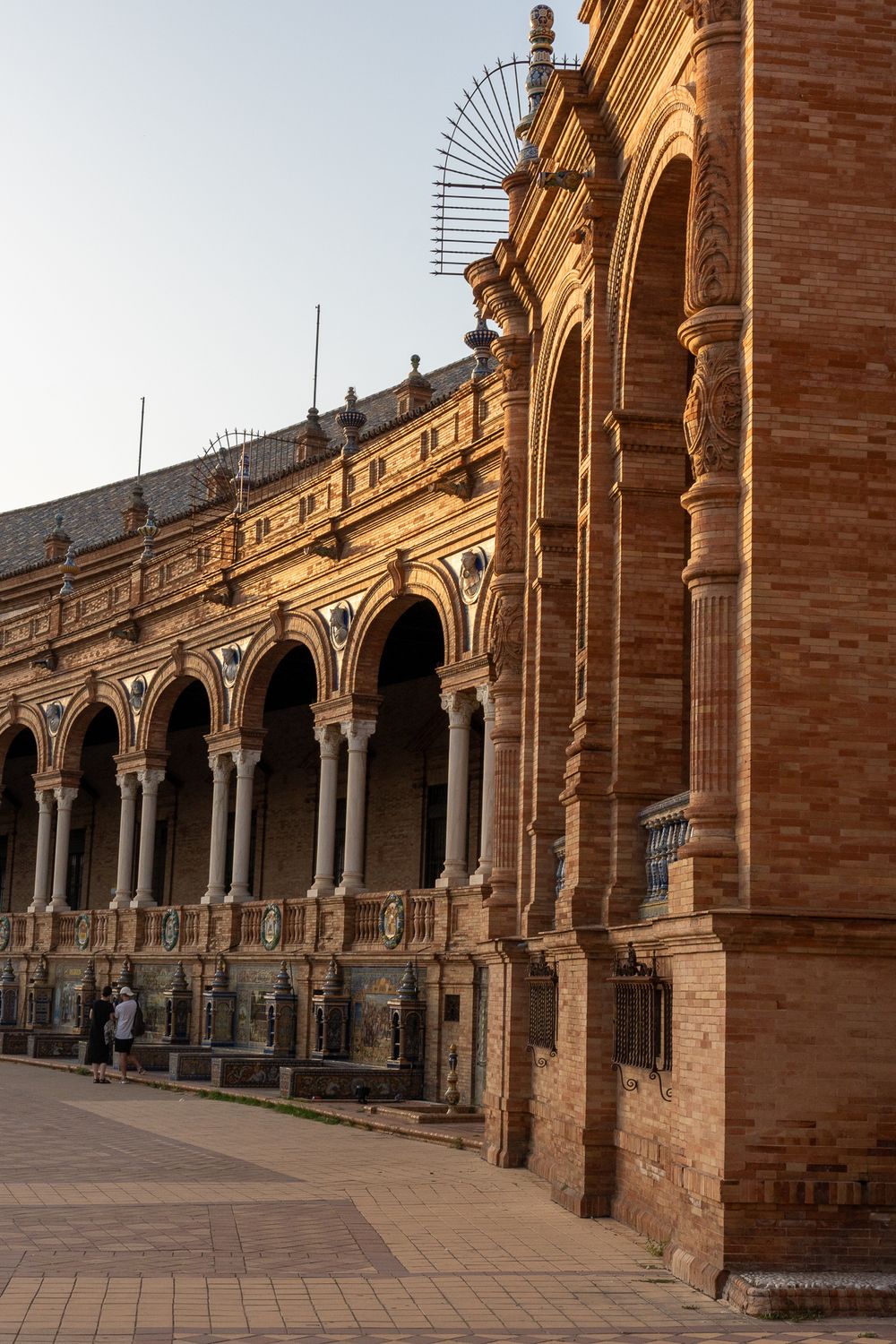 Ornate arched colonnade at Plaza de España in Seville at sunset.