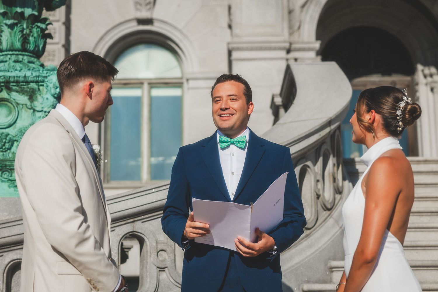 An intimate outdoor wedding ceremony takes place on the steps of a historic building.