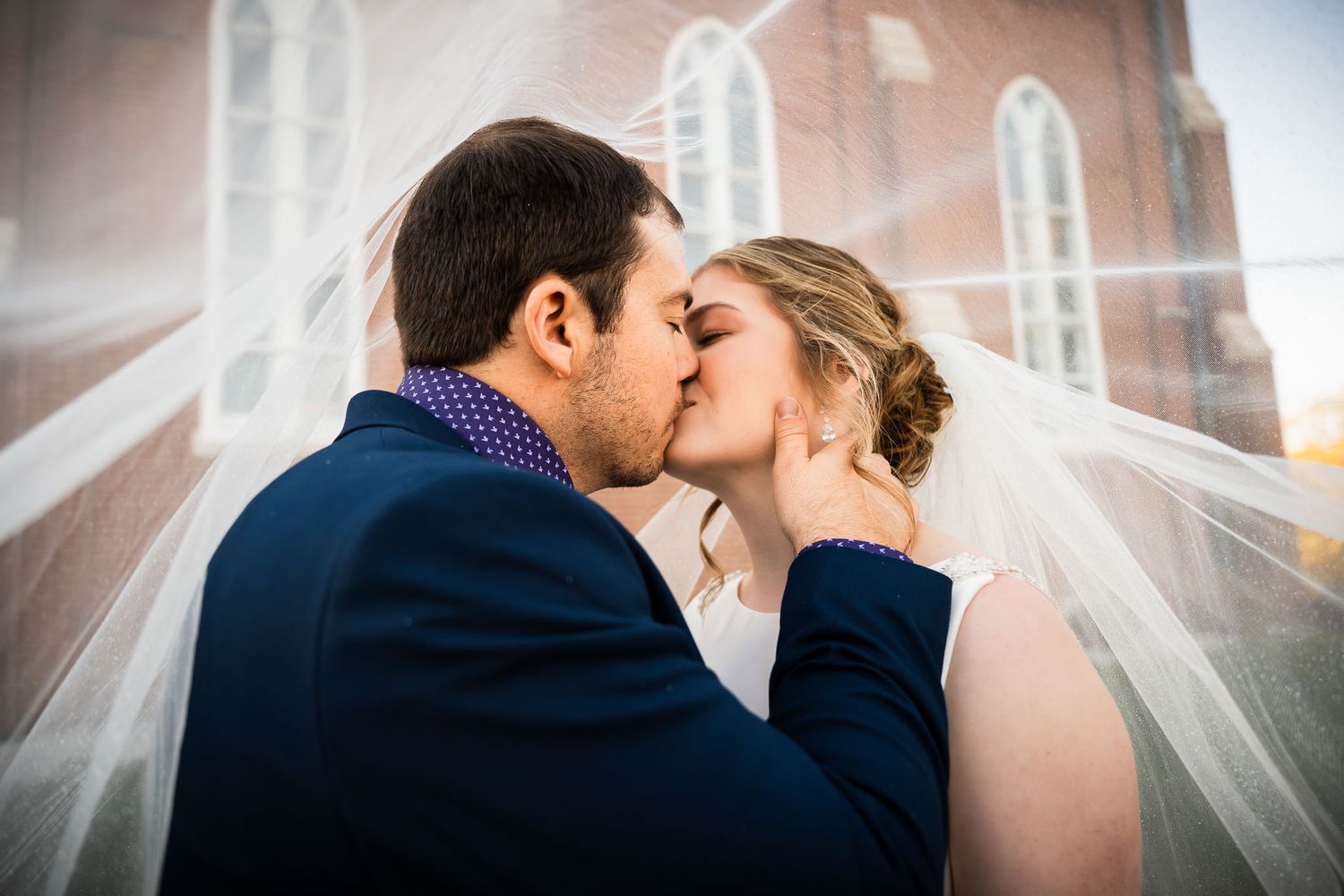 Wedding couple poses at church altar with crucifix and stained glass windows in background.