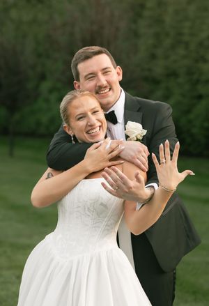 Joyful wedding couple shares a playful moment while showing off a ring.