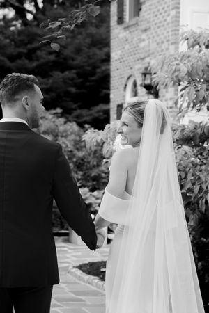 Wedding couple shares intimate moments in garden setting with flowing veil.