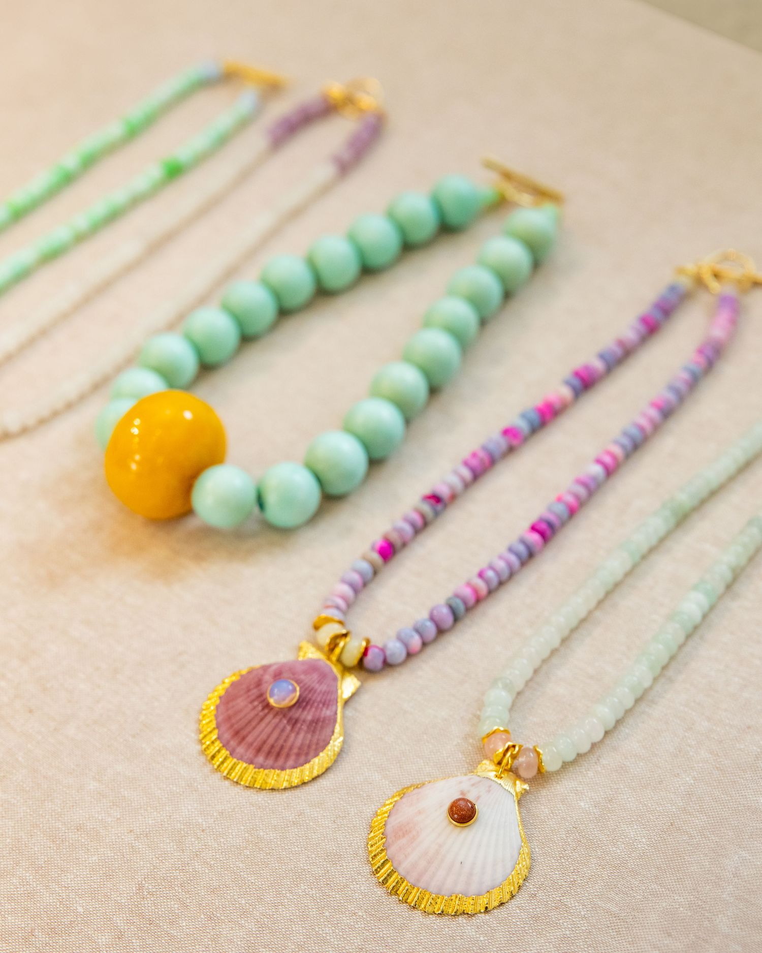 Collection of beach-inspired necklaces with seashell pendants, mint beads, and colorful accents.