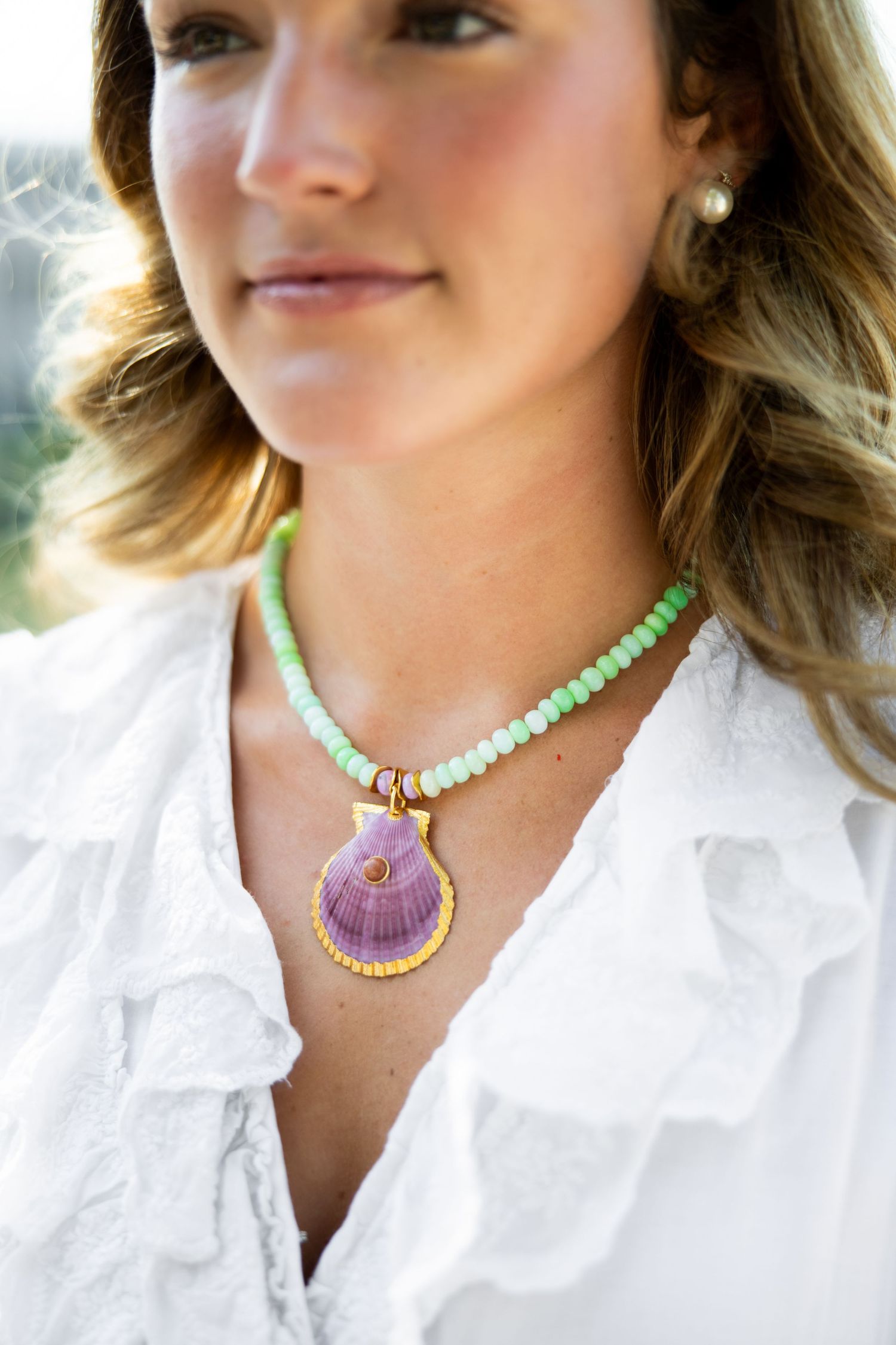 Detailed shots of layered necklaces featuring mint beads and purple shell pendant with white ruffled collar.