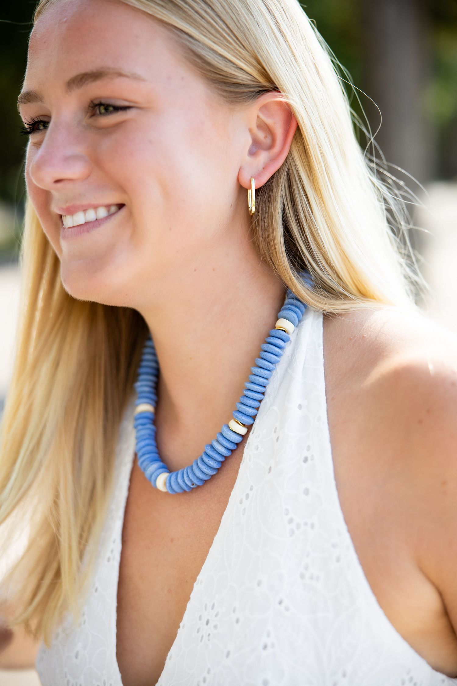 A series of photos showing a blue beaded statement necklace being worn with a white summer dress.
