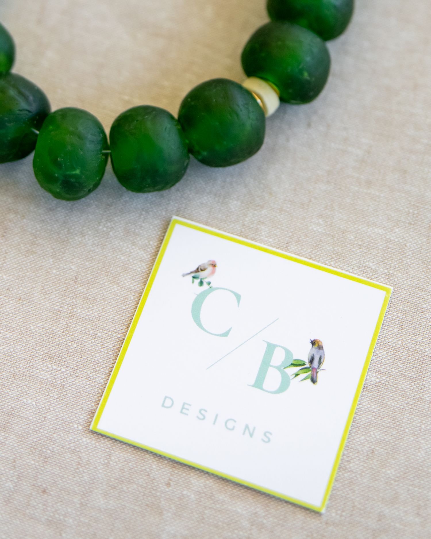 Green limes arranged next to business cards with mint and yellow accents on linen fabric.