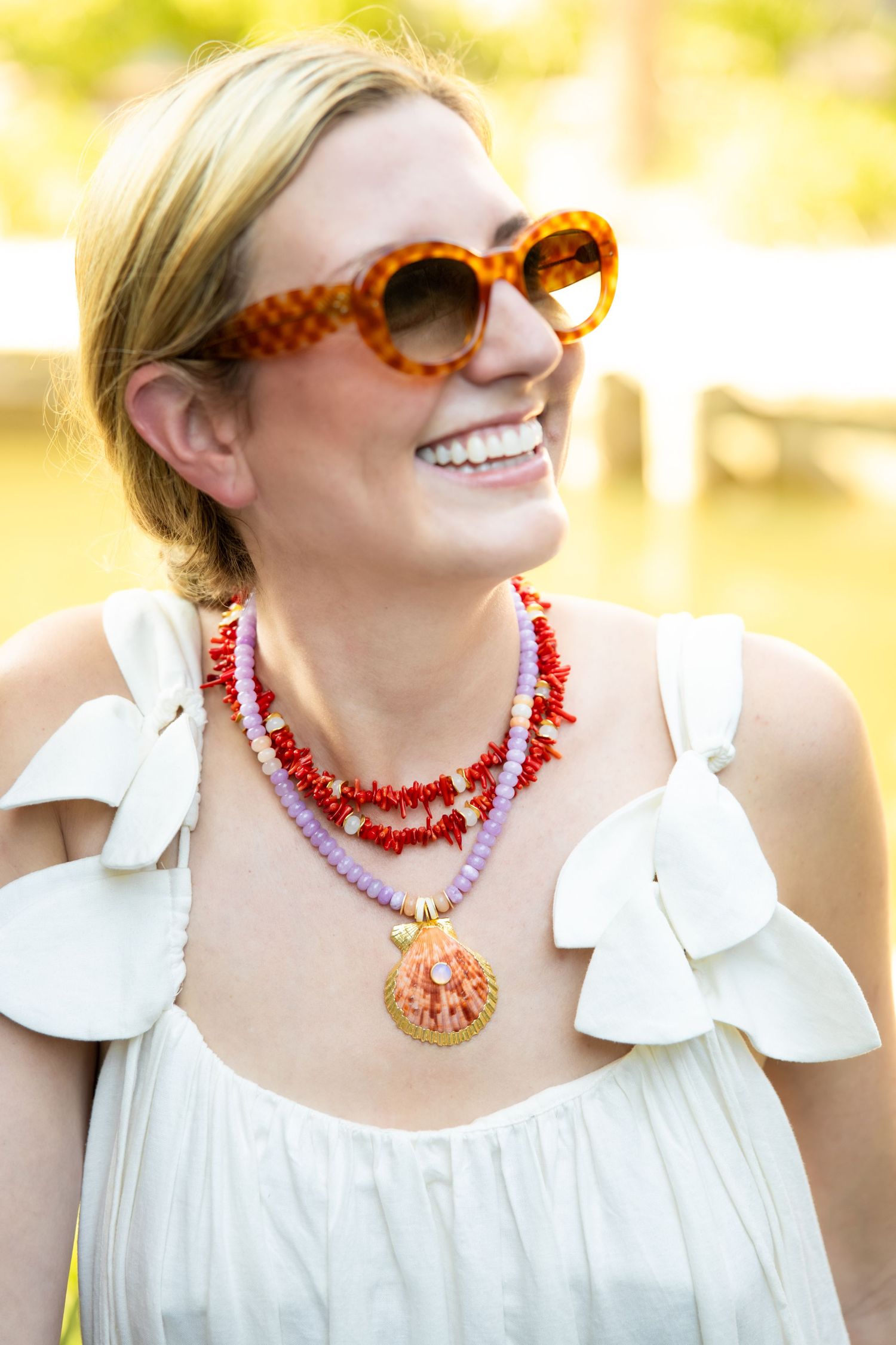 Fashion shots showing coral and pink beaded necklaces styled with a white summer dress and tortoise sunglasses.