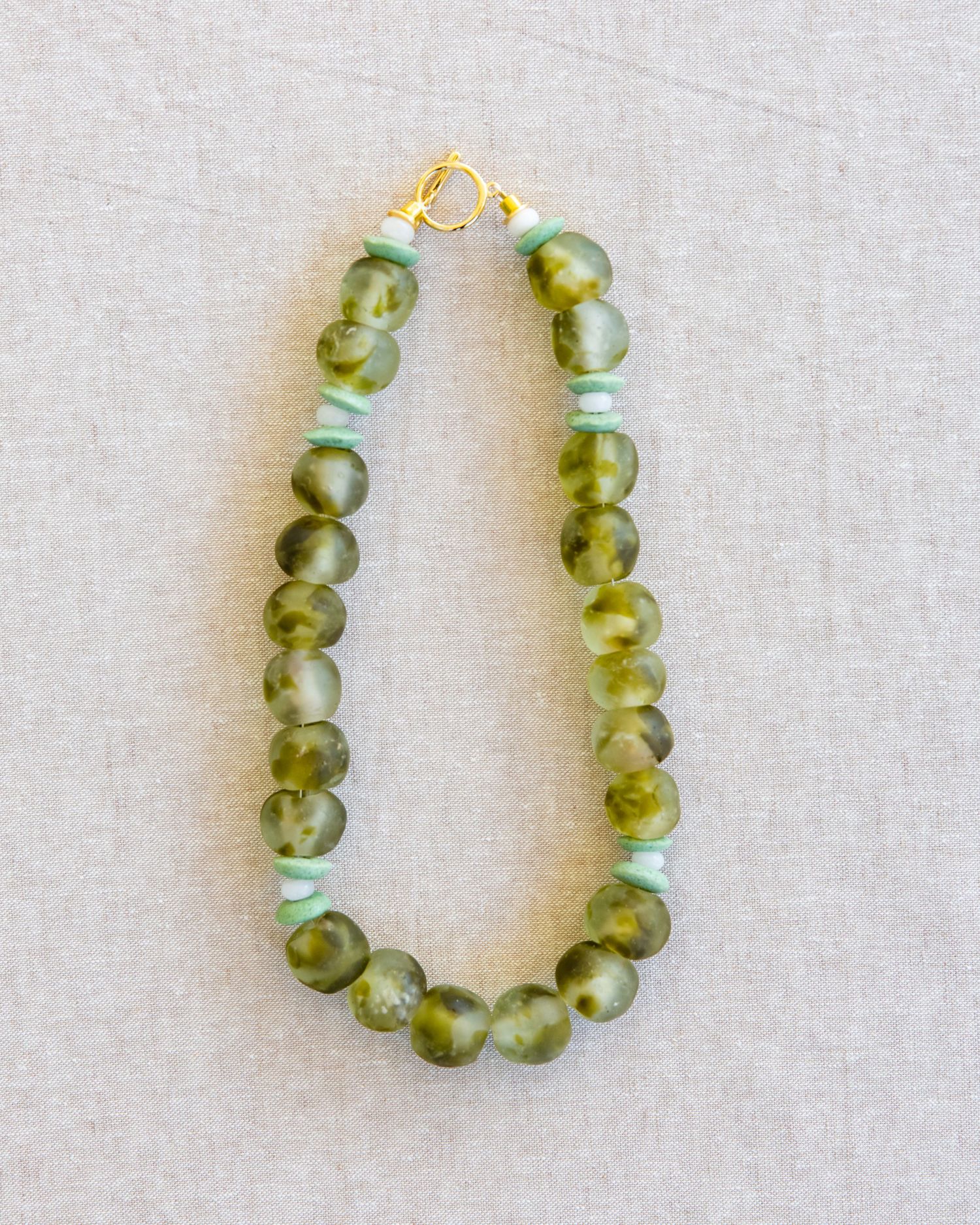 Green glass beads arranged in a curved formation against a light gray background.
