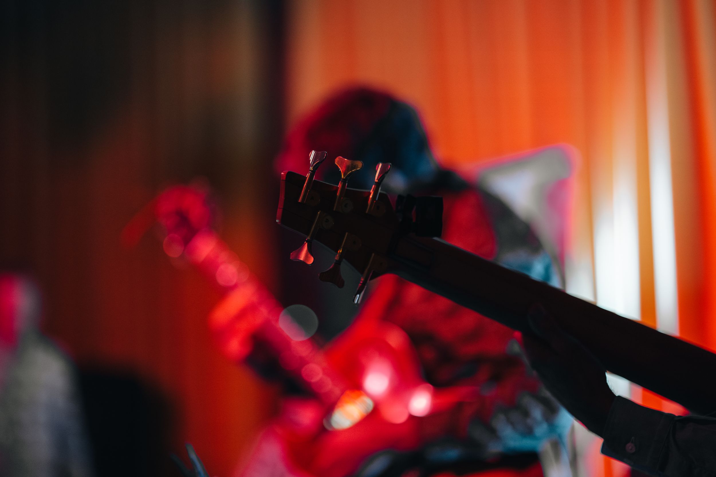 Concert venue illuminated with vibrant orange and red stage lighting during performance.