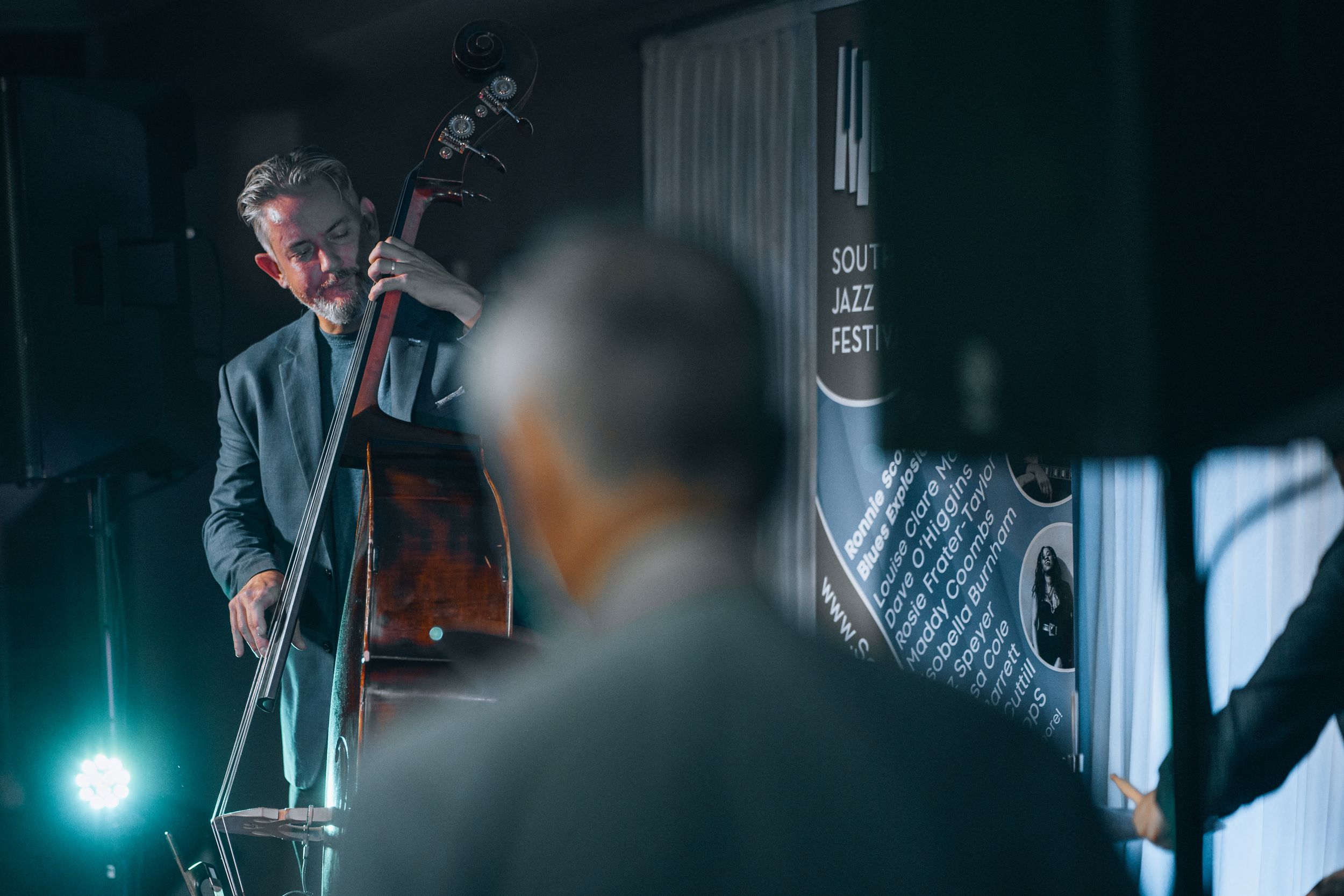 Bass player performing on stage with dramatic blue lighting.