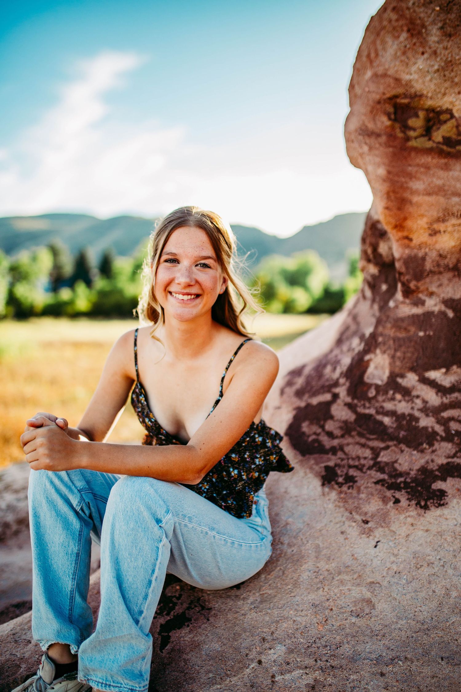 Casual outdoor portrait near red rock formations with mountains in background.