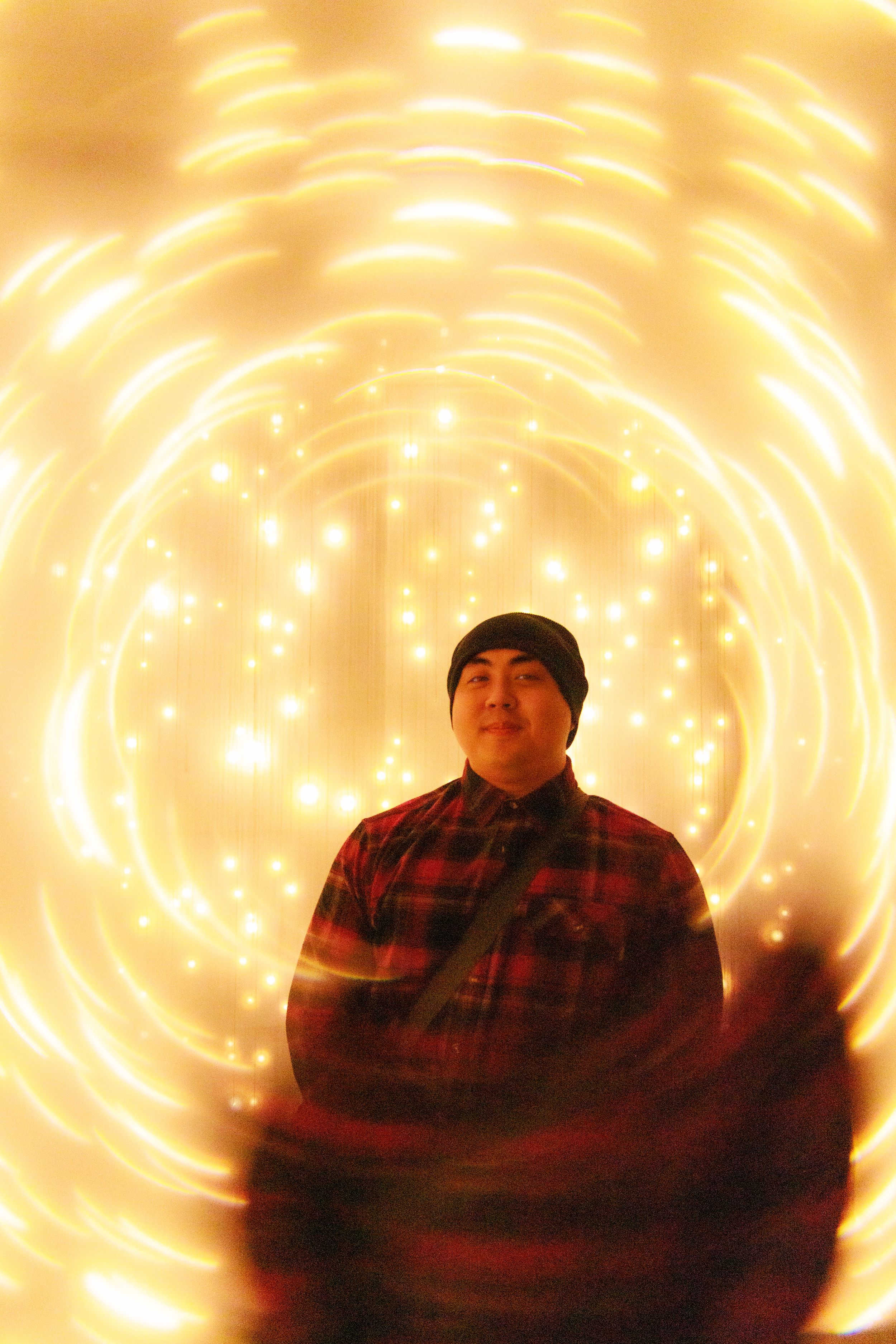 A person wearing a plaid shirt is shown in multiple poses against a glowing orange spiral light background effect.