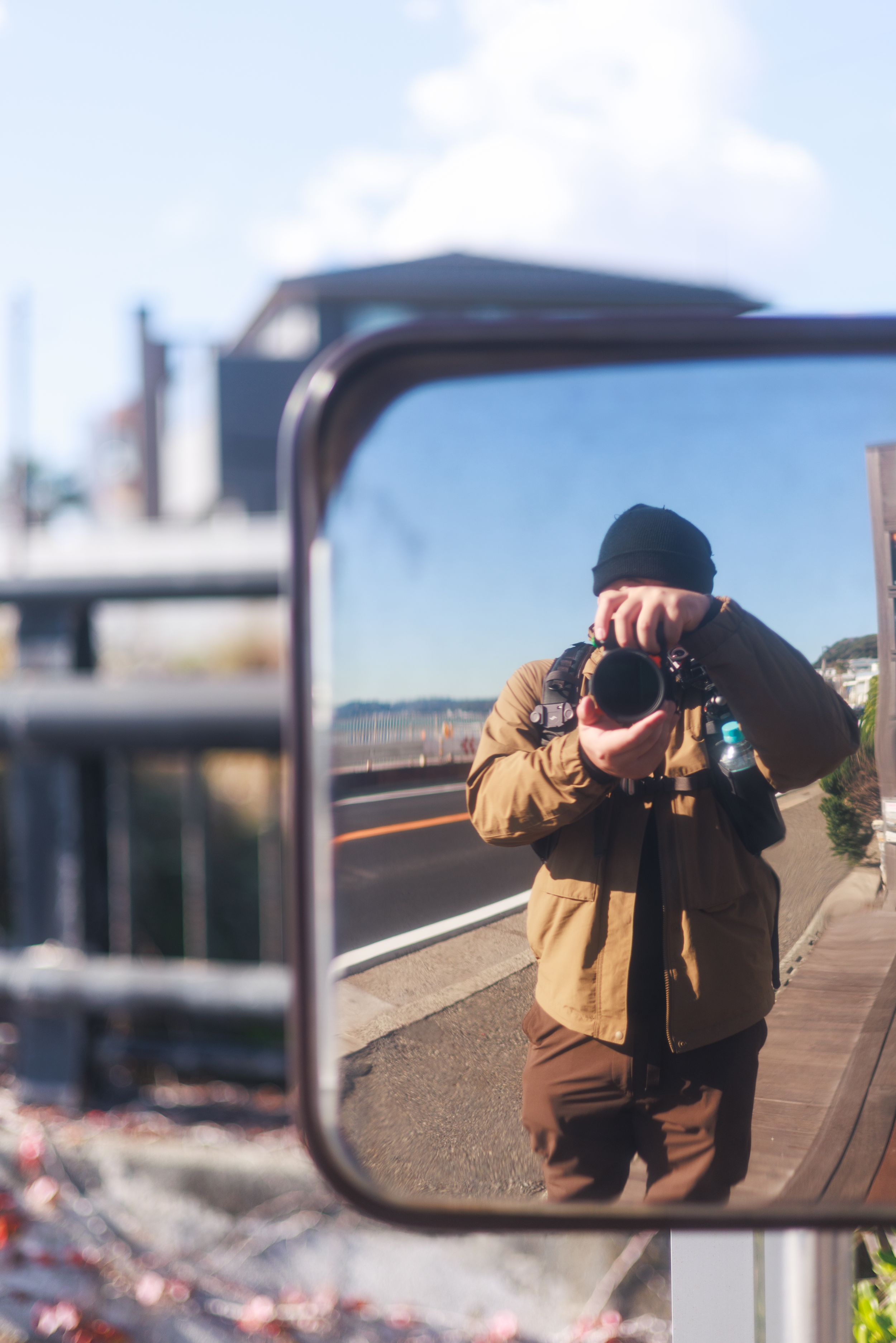 A series of mirrored reflections show a photographer in a brown jacket taking self-portraits in various outdoor settings.