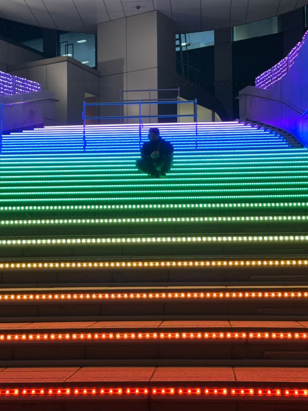 Rainbow LED lit staircase in modern building with colorful illuminated steps.