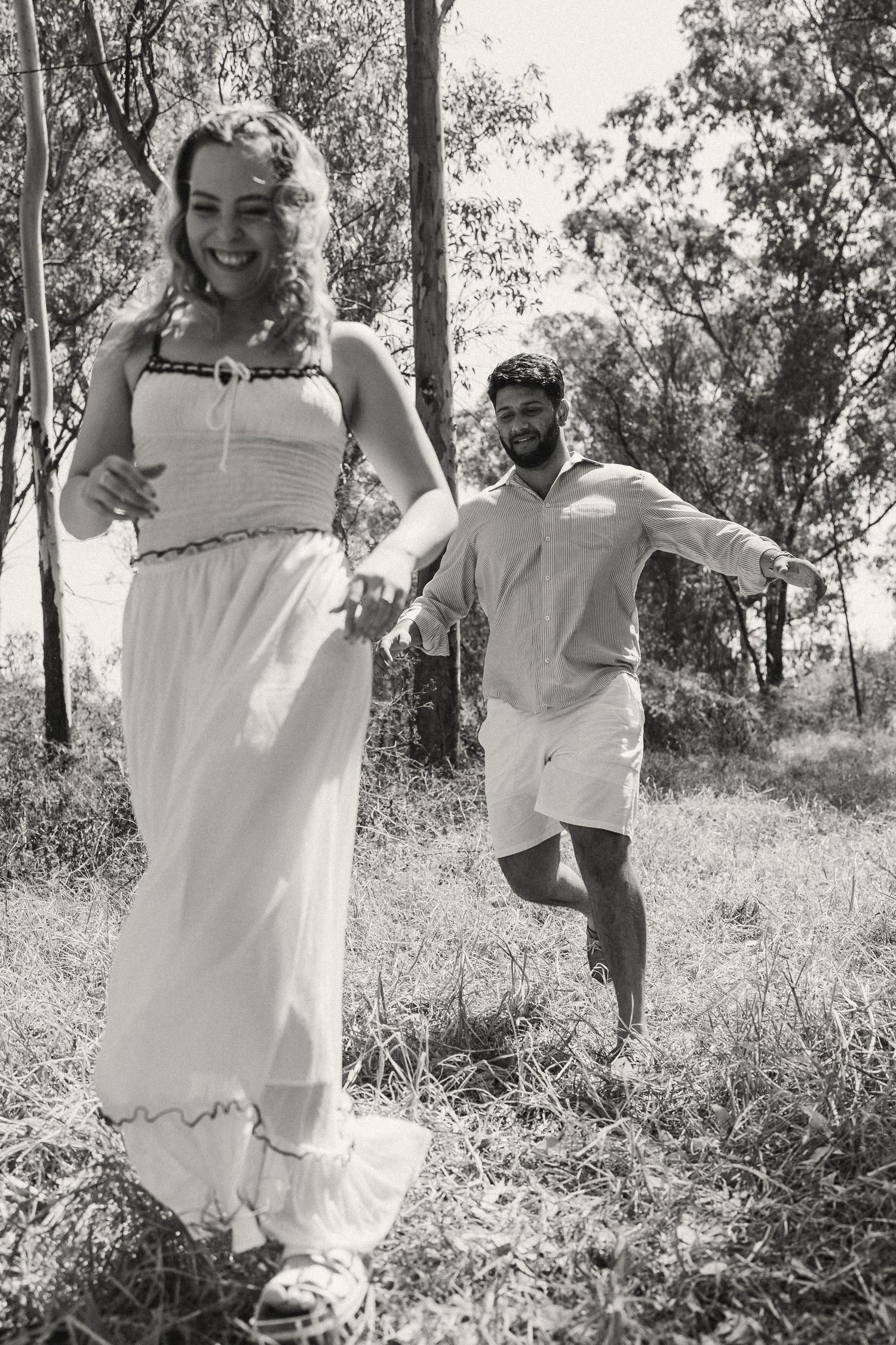 A joyful moment captured in black and white as people run through a eucalyptus grove.