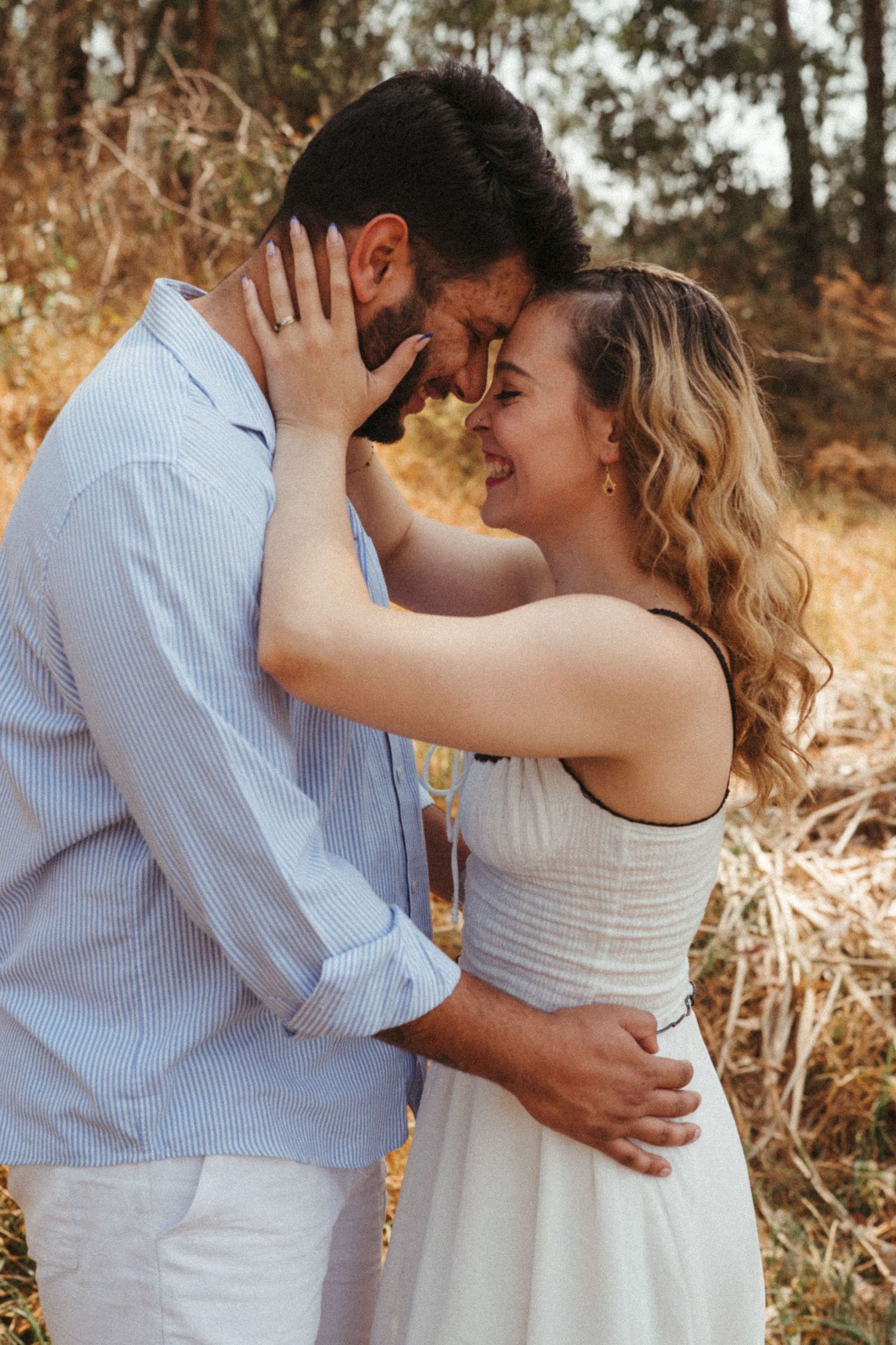 Intimate couple portrait showing loving embrace against rustic woodland background.