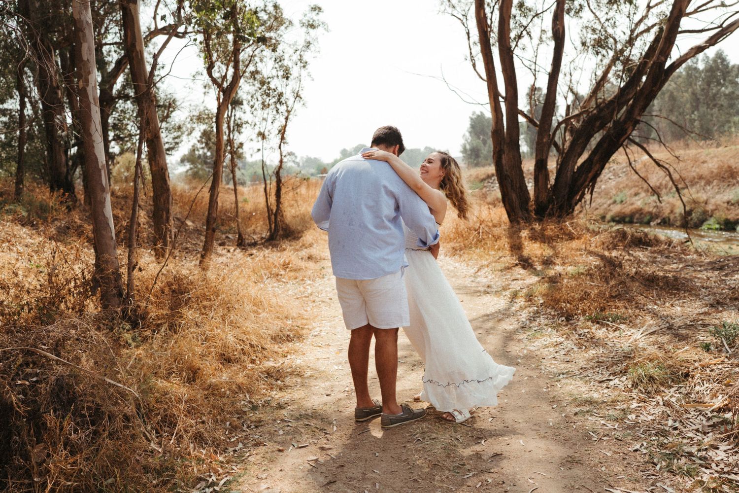 Wide angle view of couple walking together on rustic forest path in summer attire.