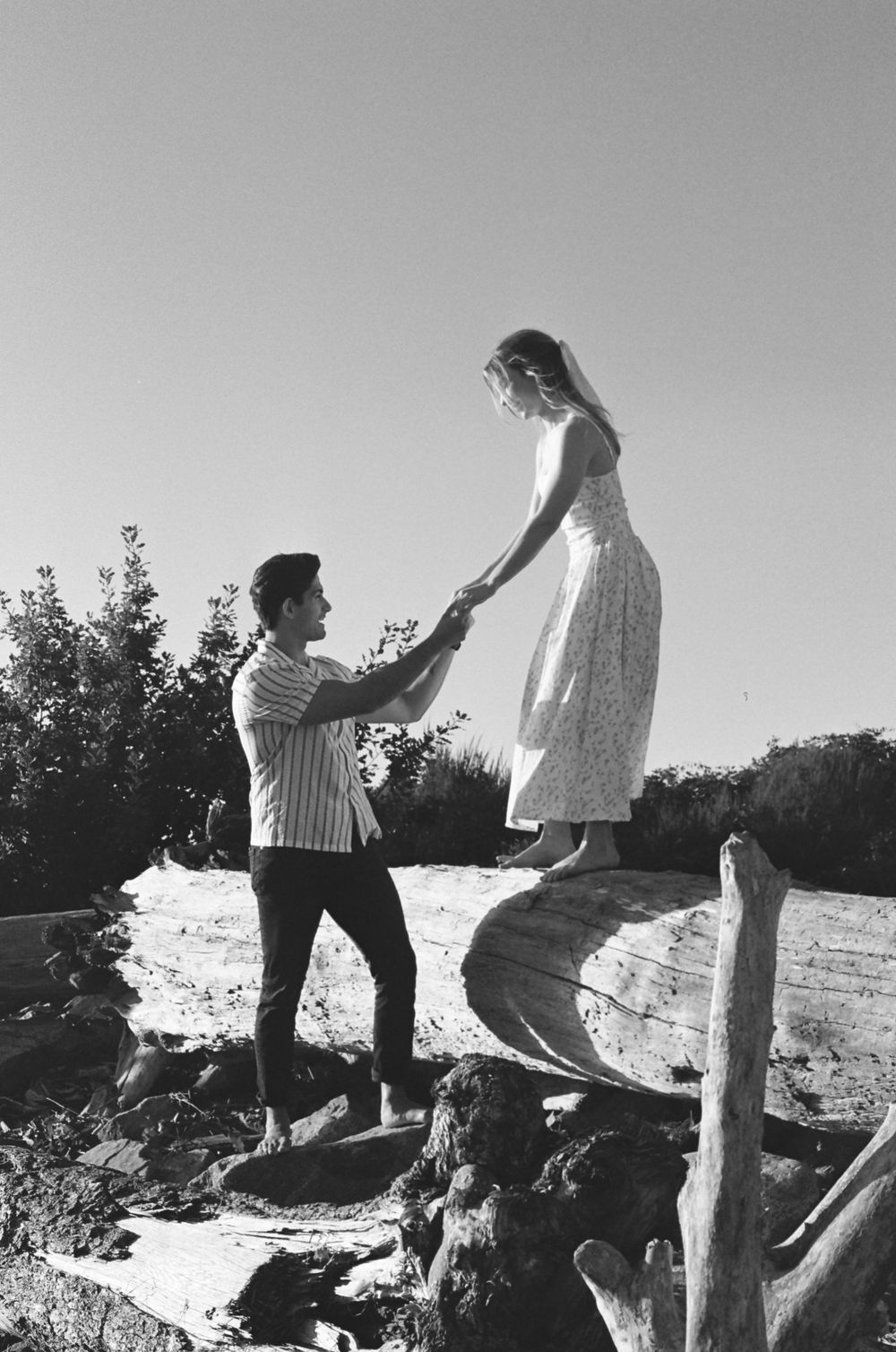 Black and white sequence of two people playing on rocks outside.