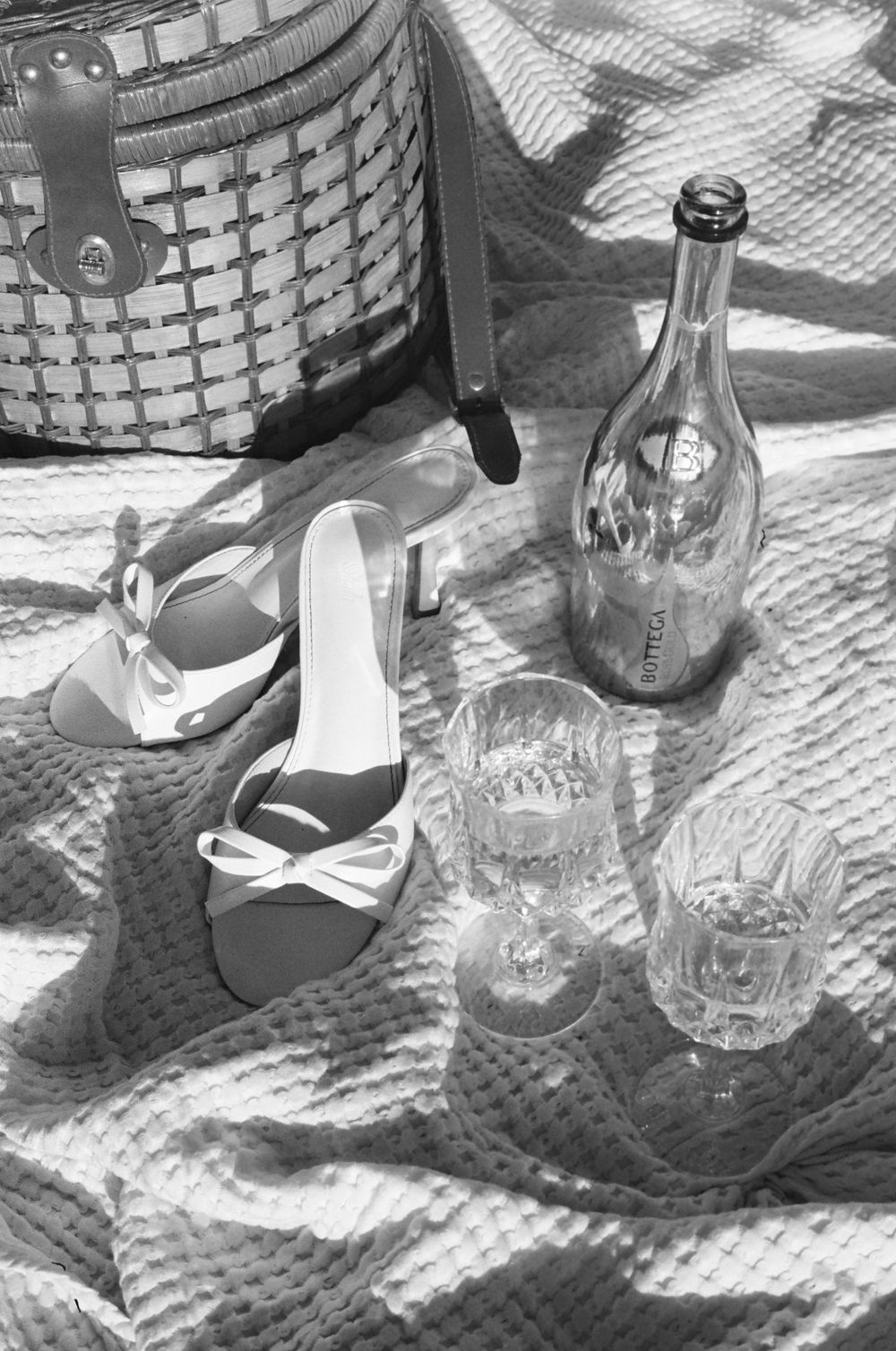 Collection of bottles and flip flops casting shadows on a textured blanket.
