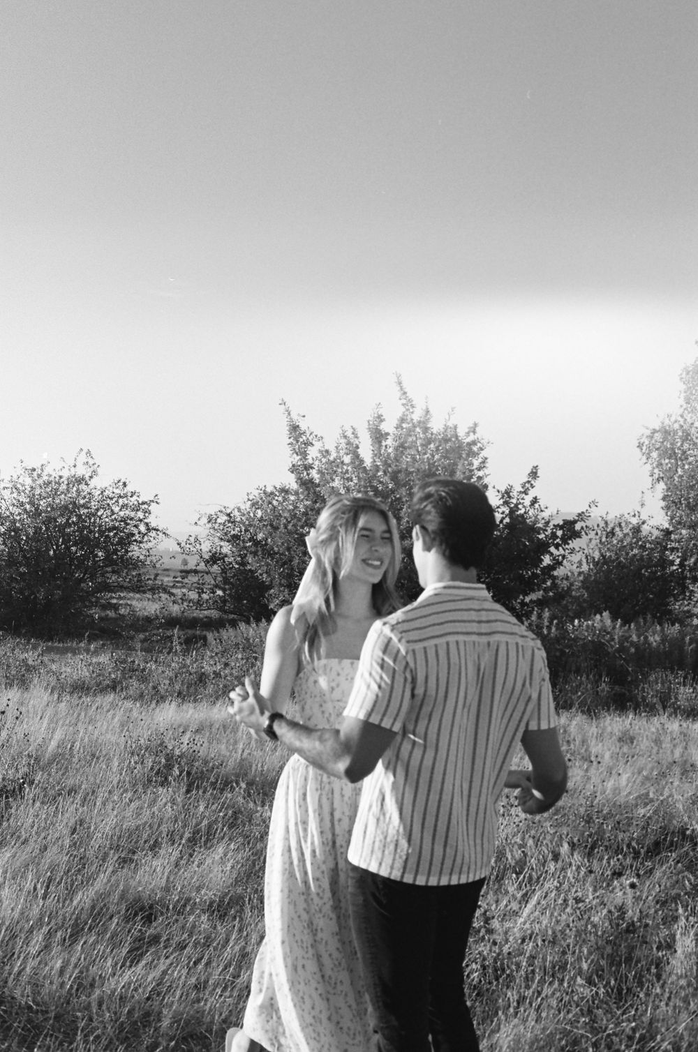 Black and white sequence capturing a dance between two people in a grassy field.