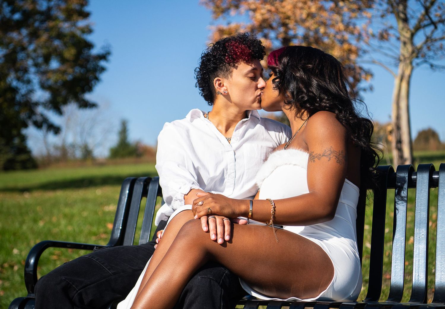 Nirel and Maddie sitting on a bench kissing
