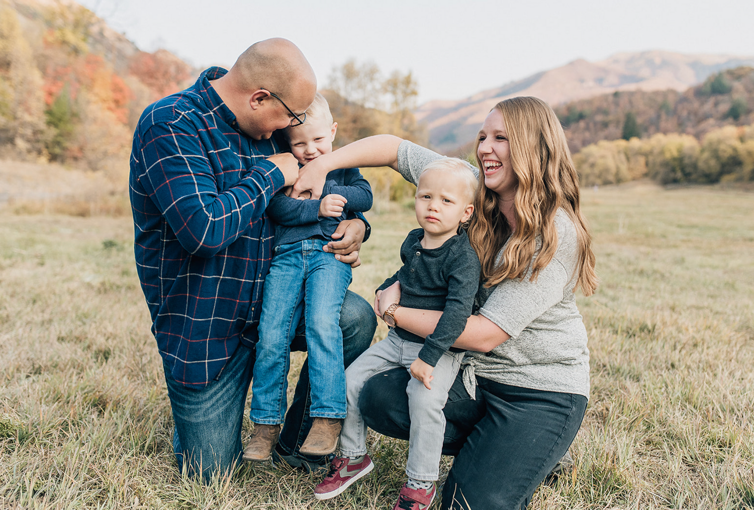 Candid family moment captured in an autumn field with warm fall colors.