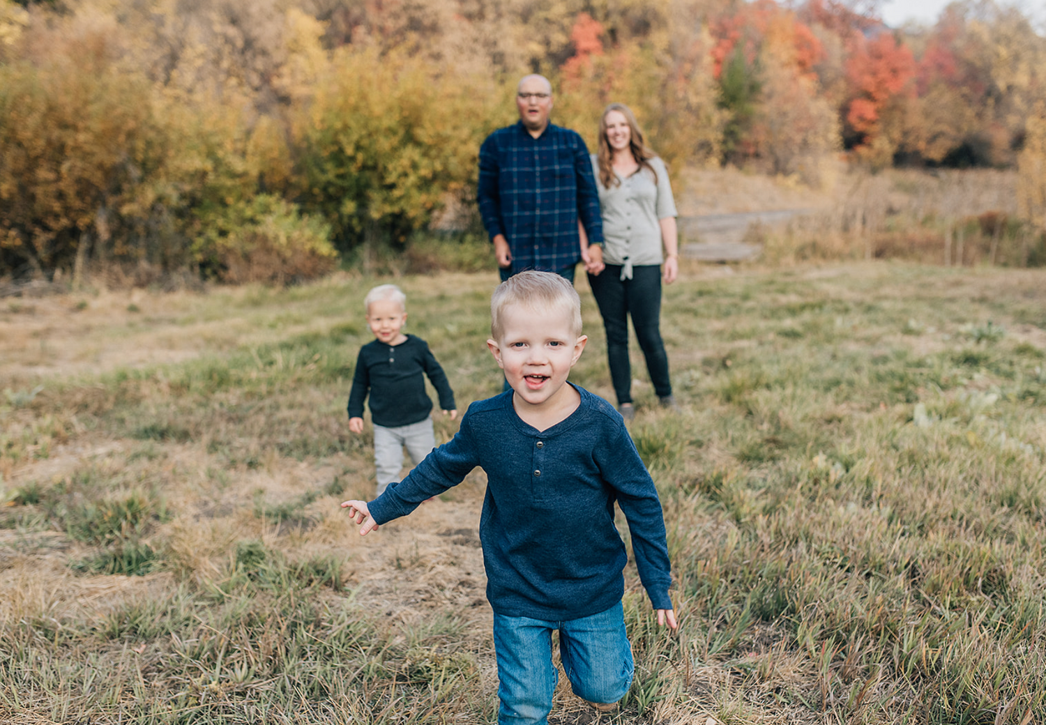 Candid lifestyle family photography in a golden autumn meadow.
