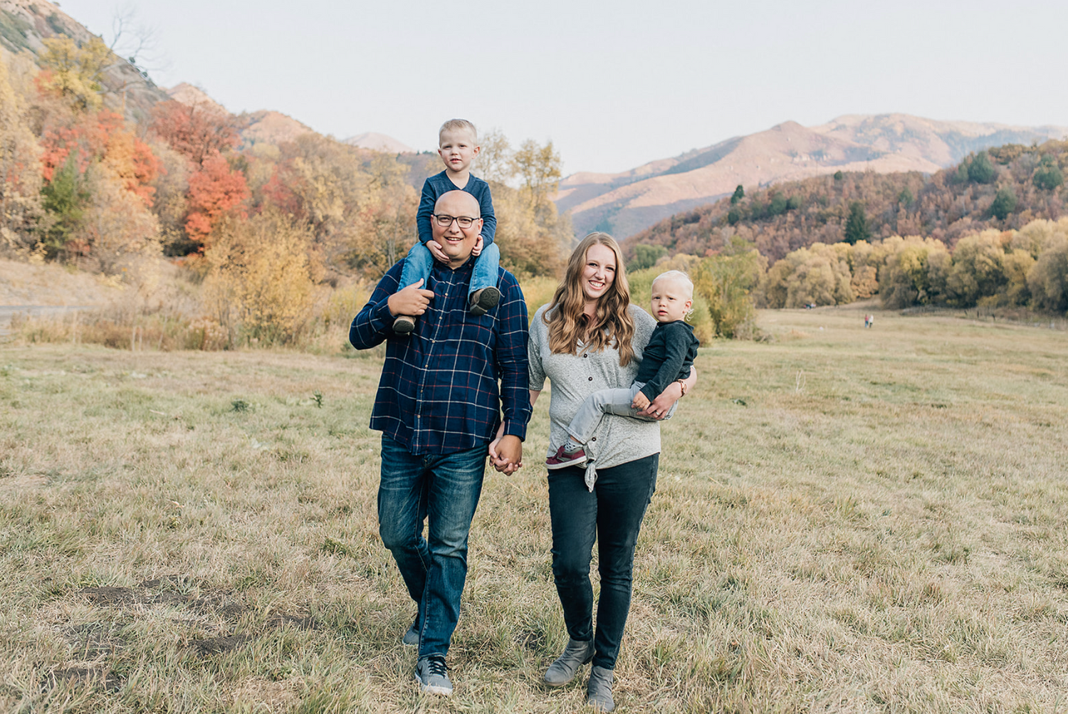 A group walks together through an autumn field with mountains in the background on a sunny day.