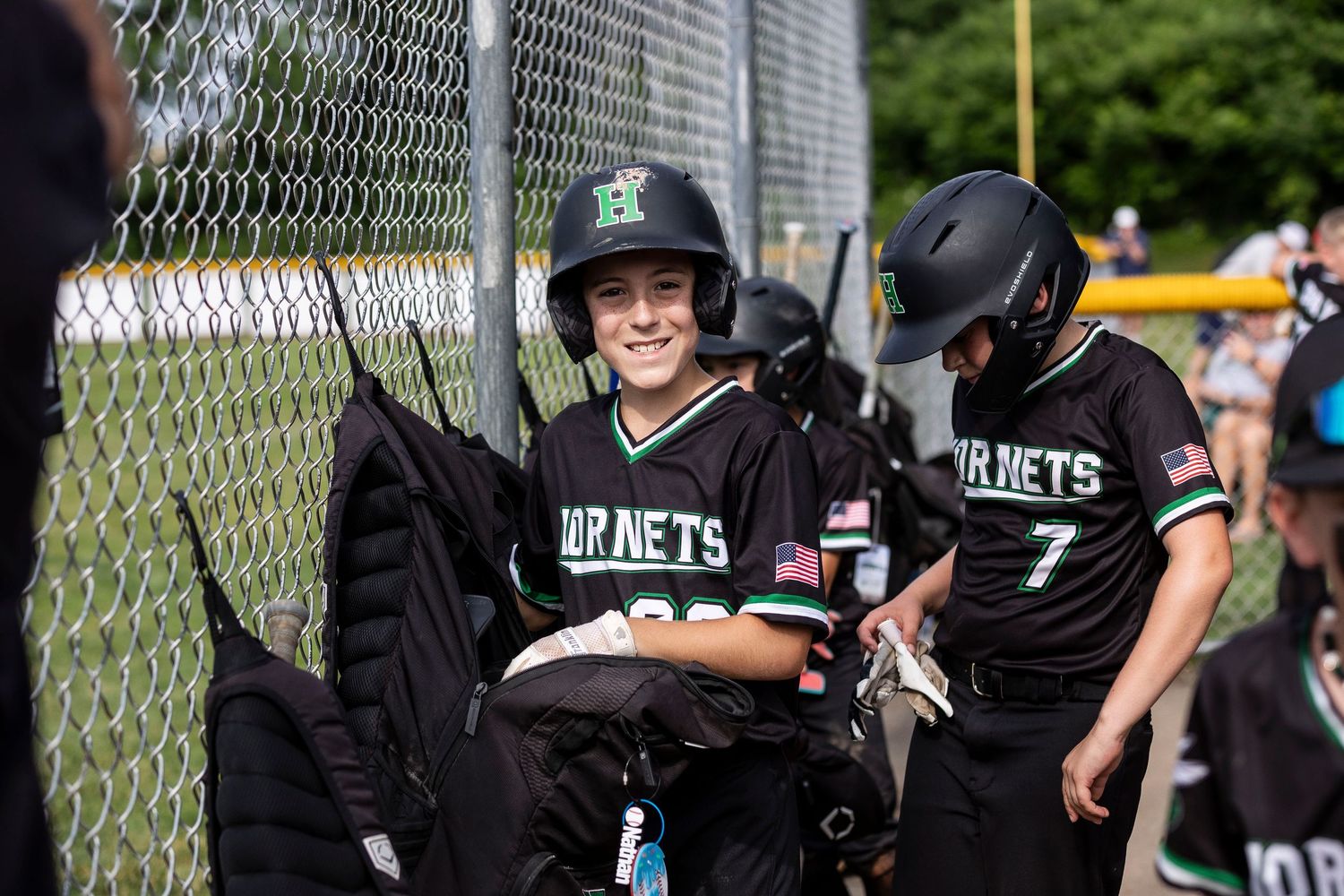 Baseball players in black jerseys gather near a chain link fence during a game.