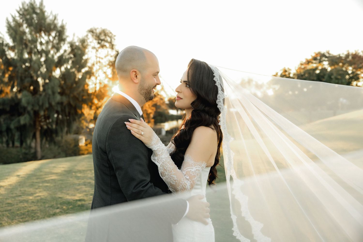 A romantic wedding portrait with a rustic windmill and vintage wagon in the background.