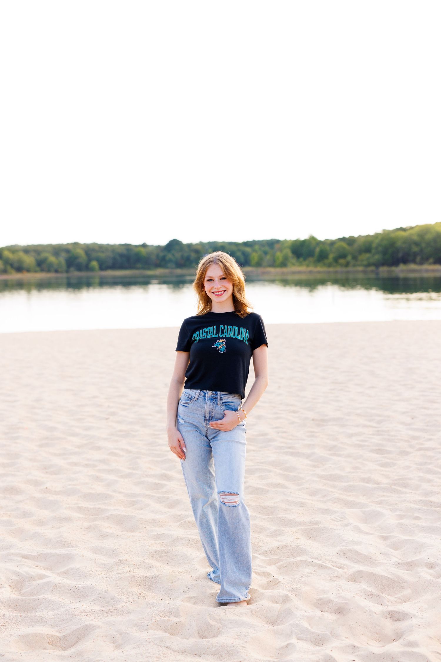 Person in casual wear posing on sandy beach during golden hour.