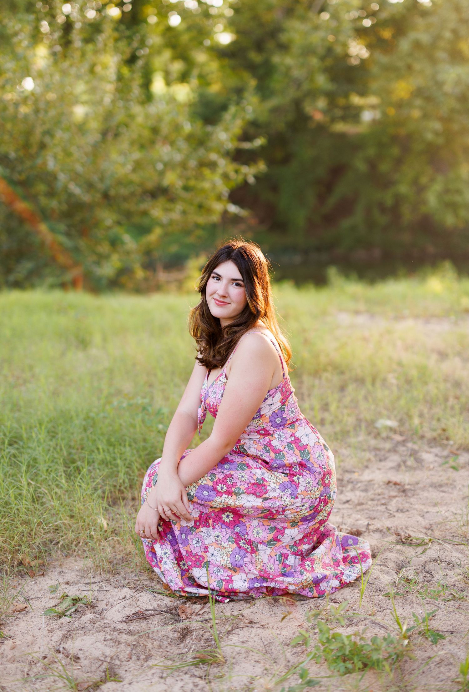 Candid outdoor portrait session featuring a pink floral dress in a grassy field.