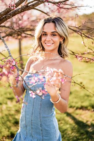 Spring portrait photoshoot under blooming cherry blossom trees with denim overalls in golden sunlight.