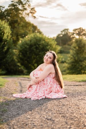 A series of sunset portraits showing someone in a pink floral dress sitting on a gravel path.