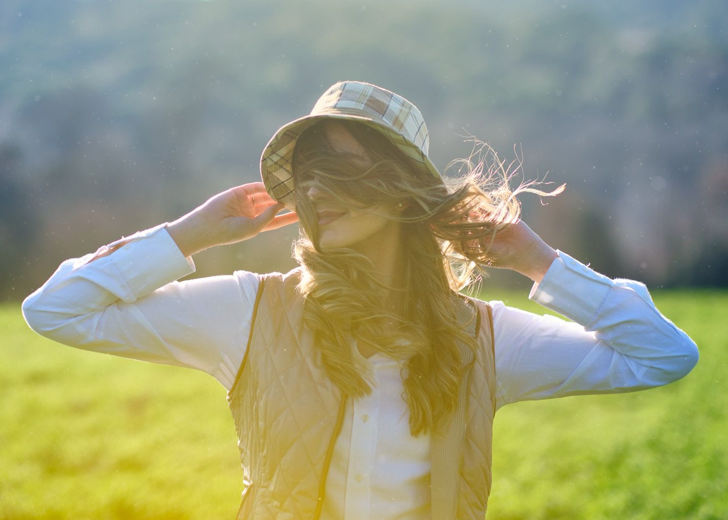 mujer joven con sombrero baila en el campo al sol del atardecer