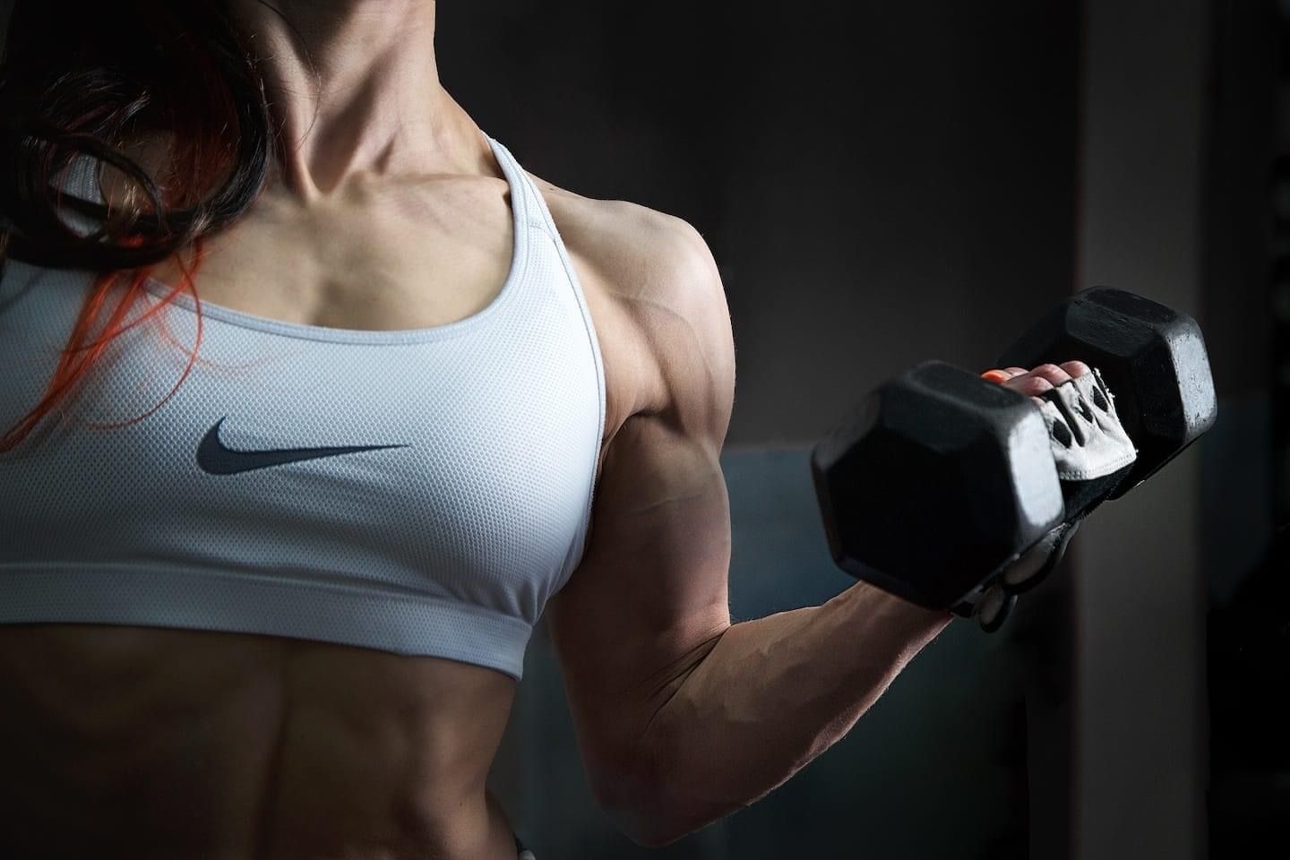 mujer deportista viste un top deportivo mientras ejercita sus biceps