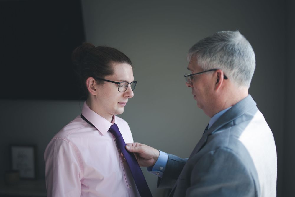 A formal dressing scene showing the adjustment of a tie.
