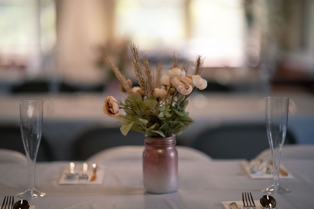 A romantic table setting with soft-focus floral centerpiece in pink vase and champagne glasses.