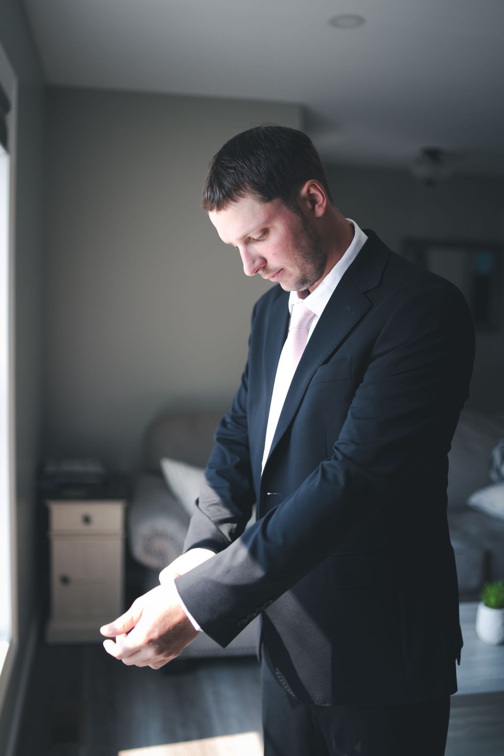 A person in formal attire adjusts their cuffs while getting ready.