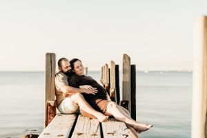 Couple sharing romantic moment on wooden dock by ocean at sunset.