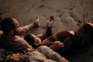 Couple relaxing together on sandy beach during sunset.